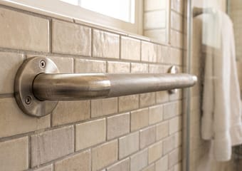 Grab bar mounted on a tiled bathroom wall