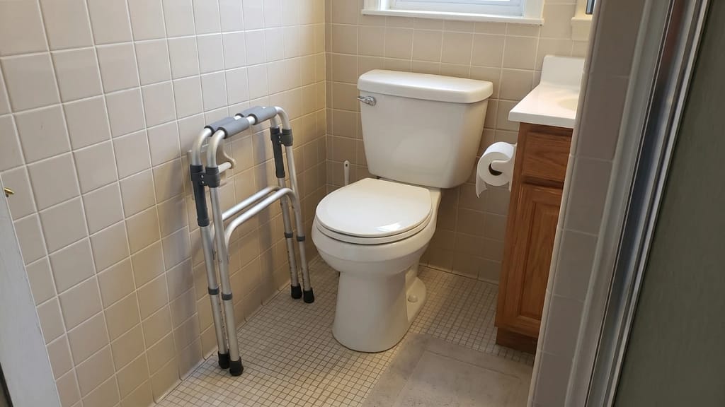 Folding toilet safety frames shown beside a toilet in a small bathroom